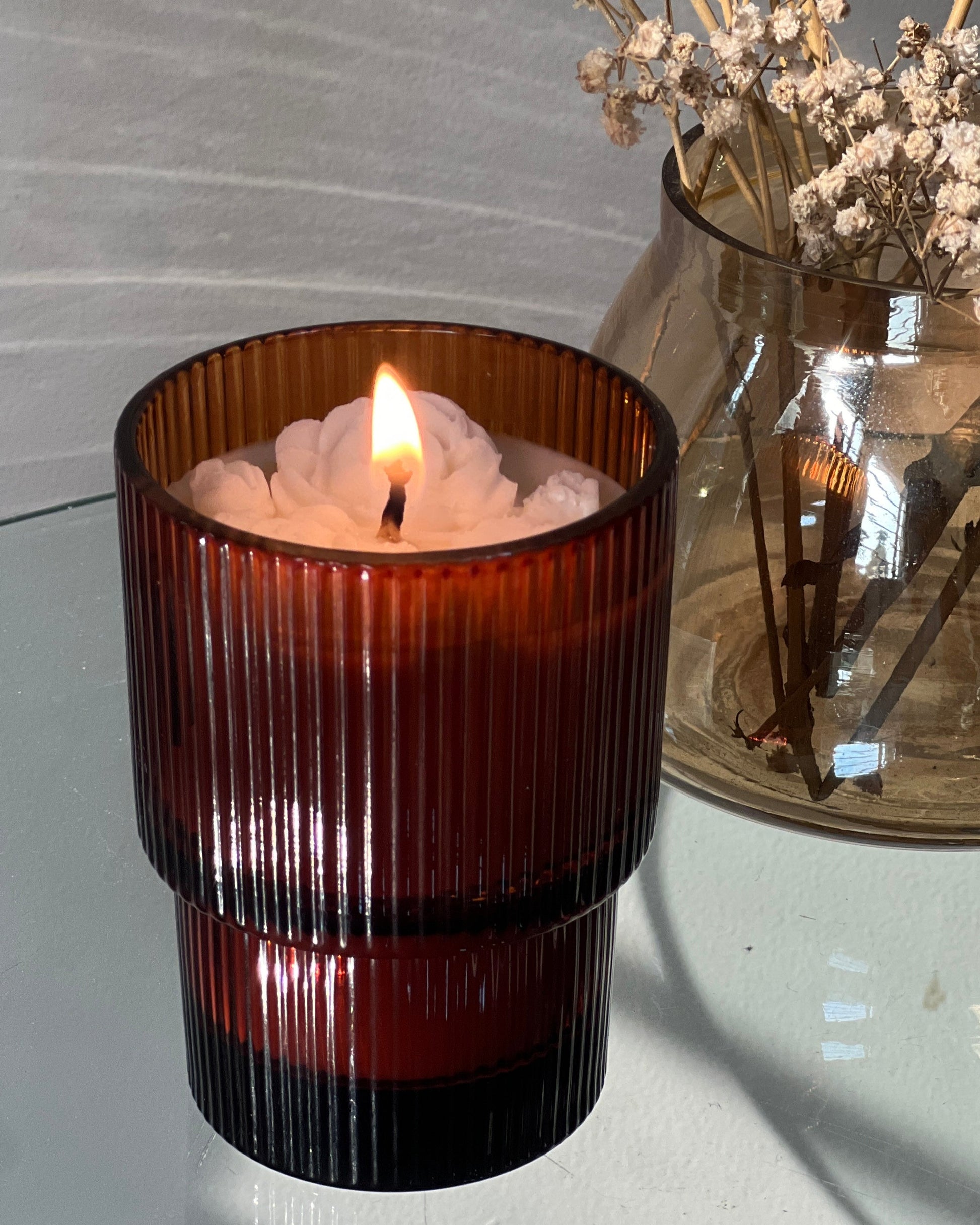Brown ribbed candle in a glass holder with a blurred background