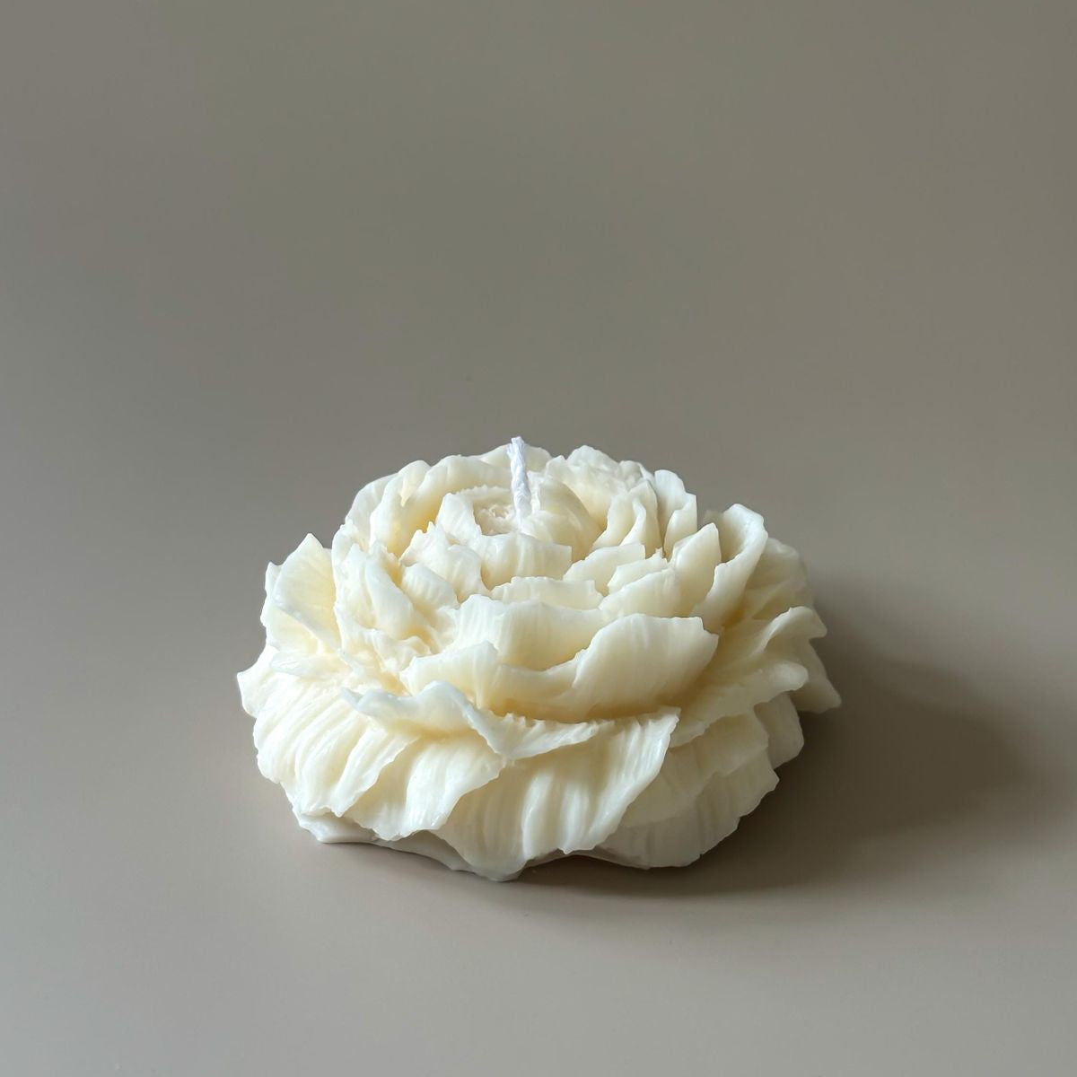 White flower-shaped candle on a beige background