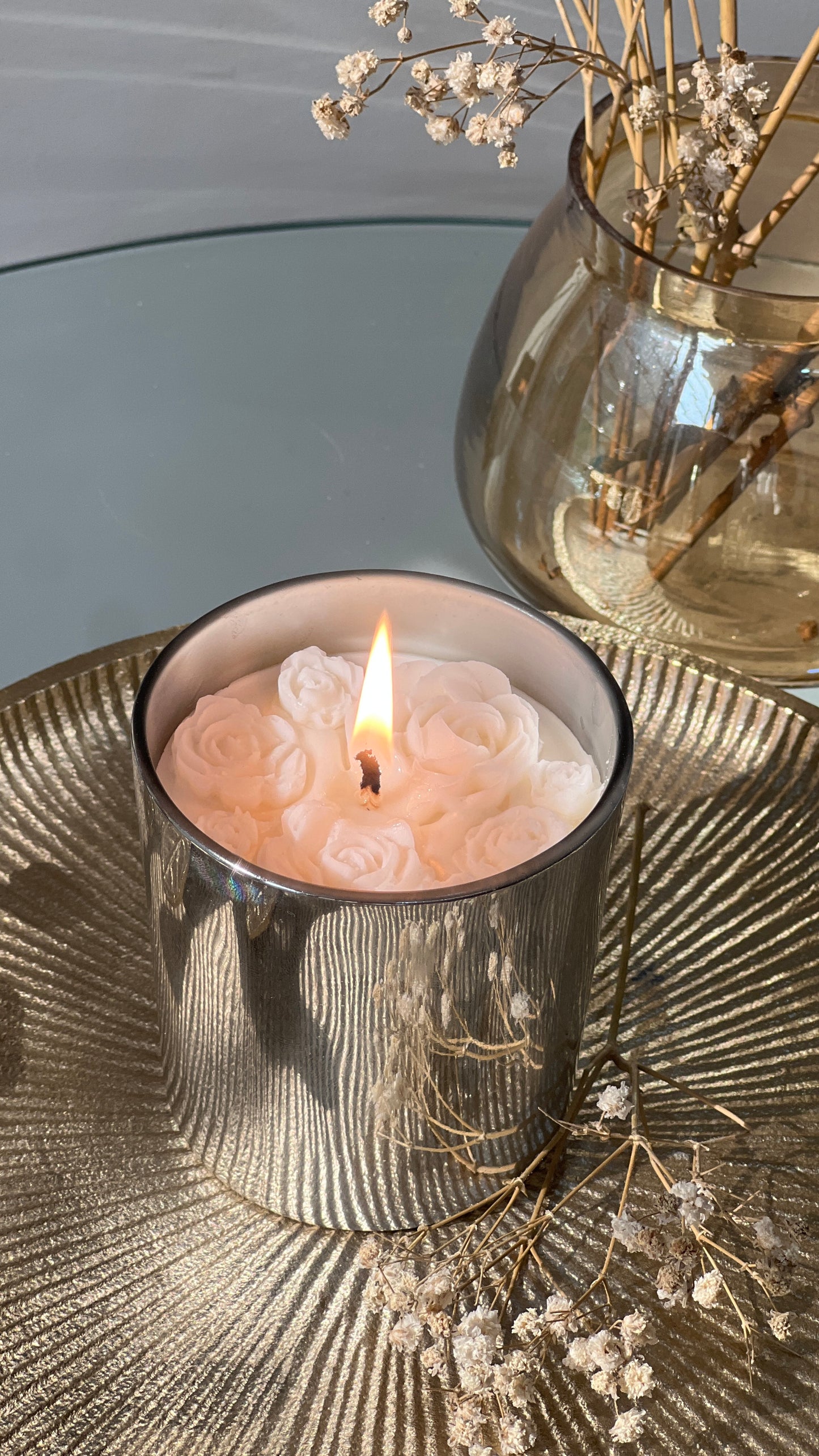 Candle in a decorative holder with flowers on a textured surface