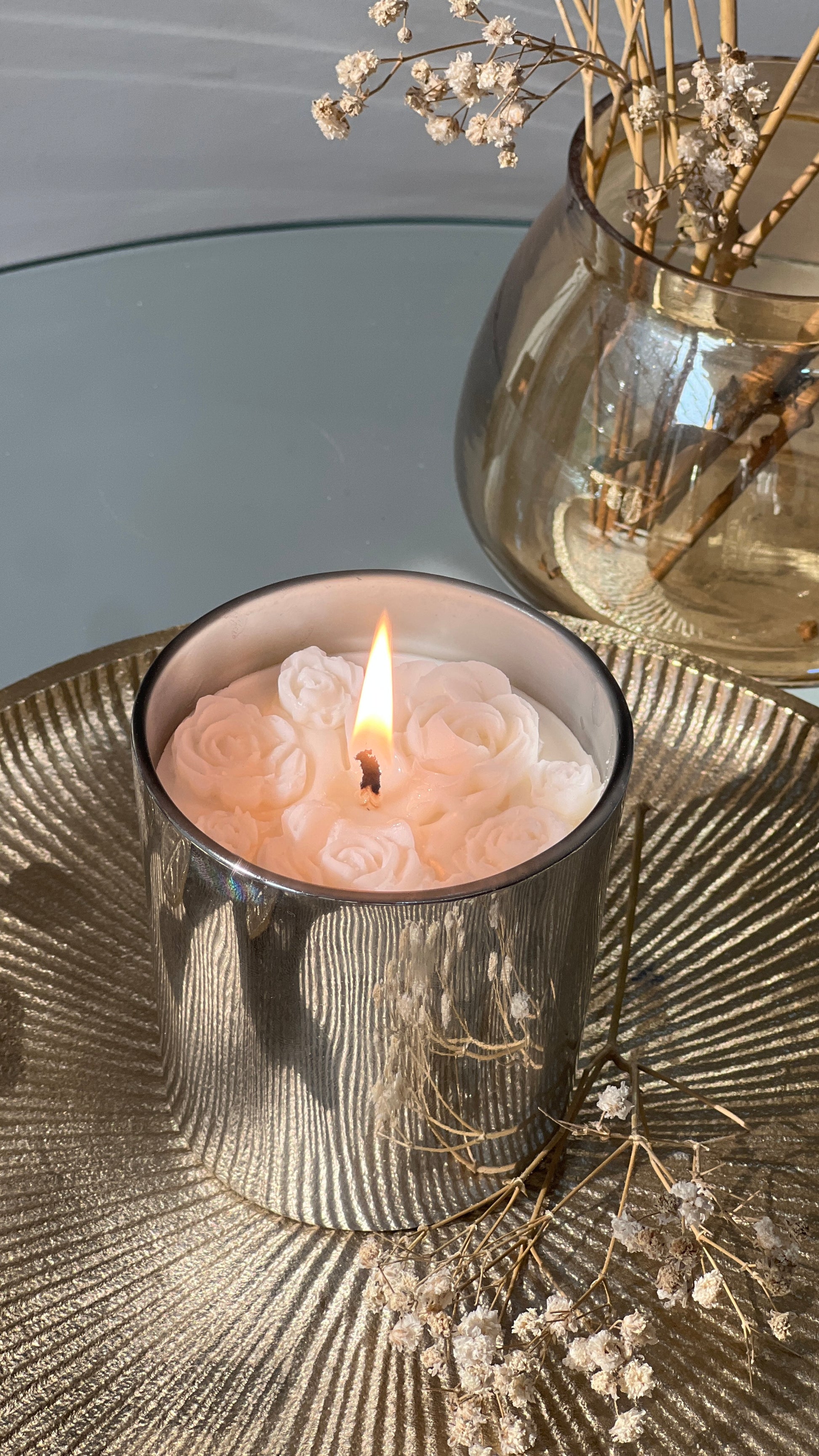 Candle in a decorative holder with flowers on a textured surface