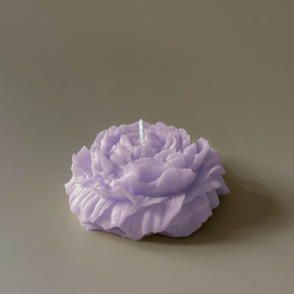 Purple rose-shaped candle on a plain background