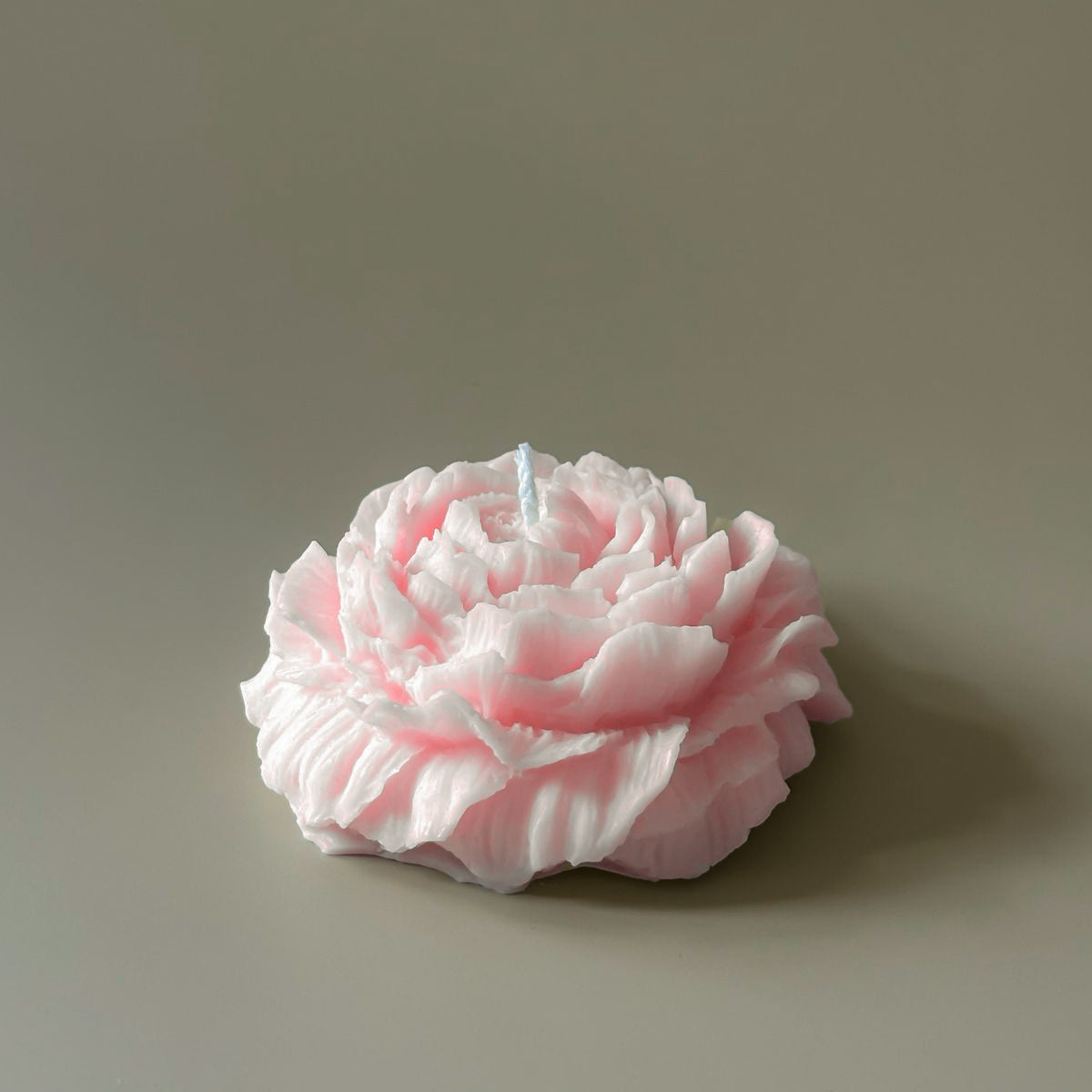 Pink flower-shaped candle on a gray background