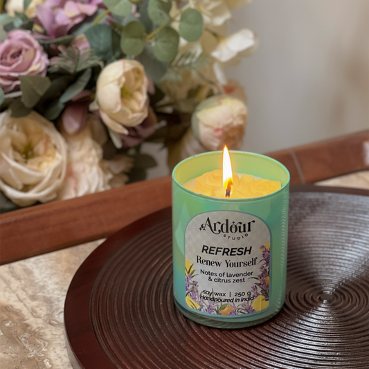 Candle with a label in front of flowers on a wooden surface