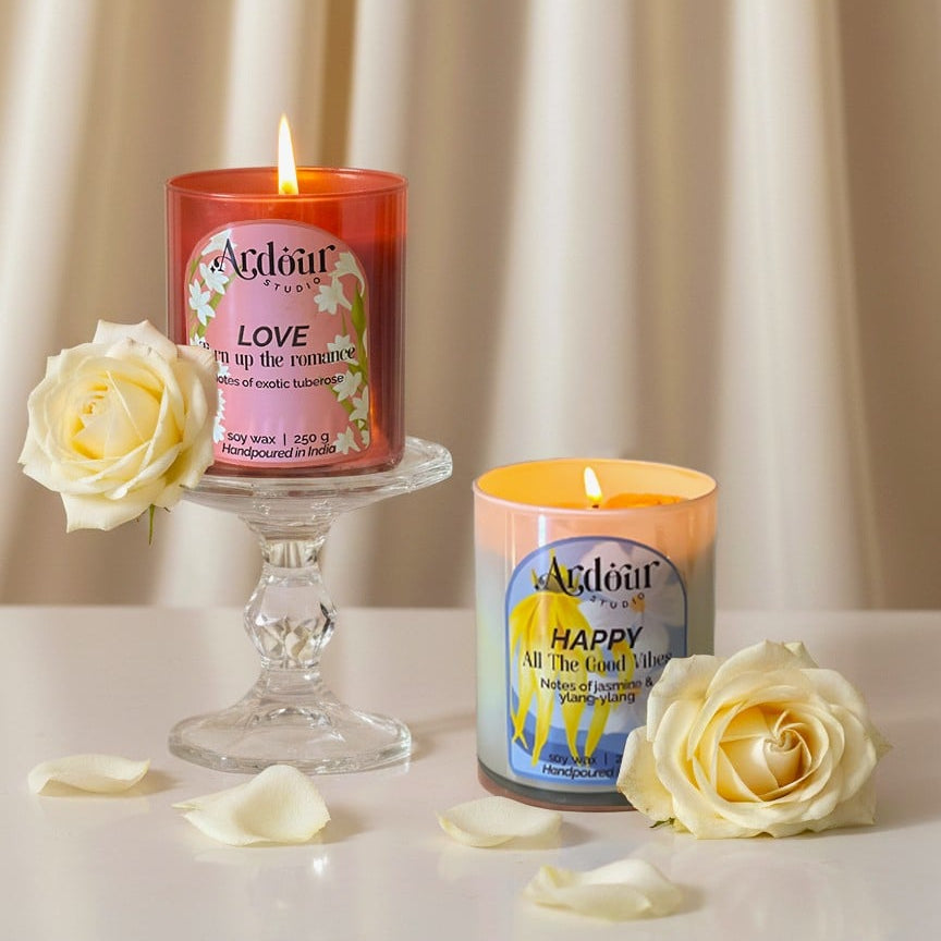 Two Aveda candles with flowers on a neutral background