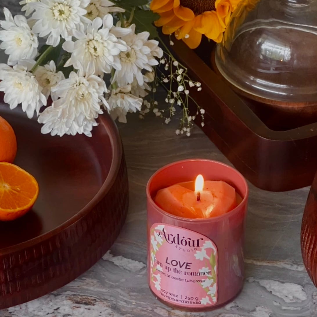 Candle with a floral arrangement and oranges on a stone surface