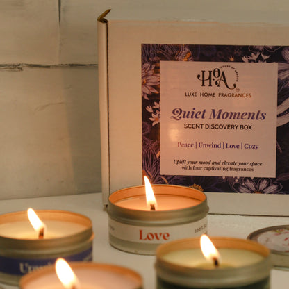 Candle tins with labels on a reflective surface, with a product packaging in the background.