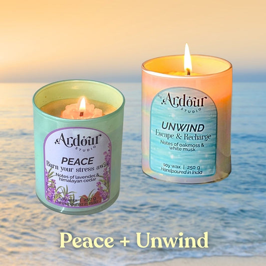 Two scented candles labeled 'Peace' and 'Unwind' on a beach with ocean waves in the background.