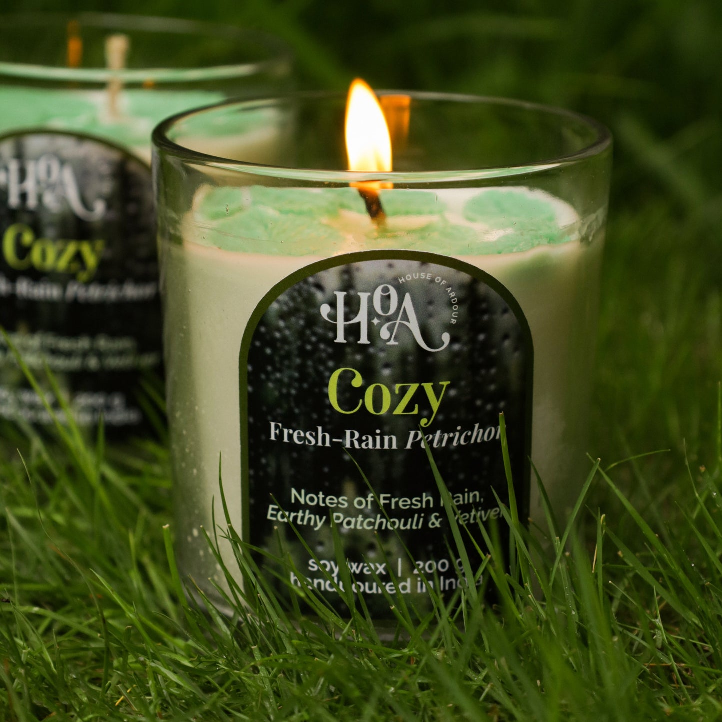 Candle labeled 'Cozy' on grass