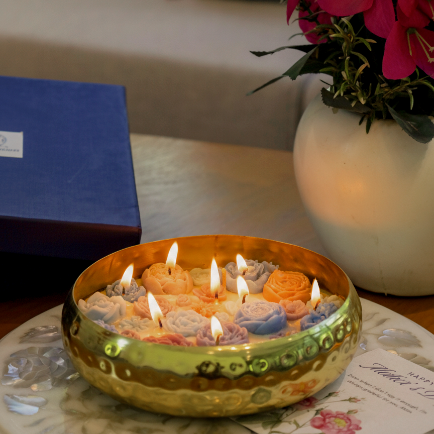 Large decorative golden urli bowl candle on a table with flowers and a gift box in the background diwali gift