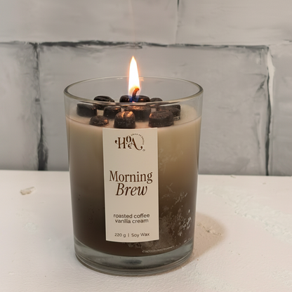 Candle labeled 'Morning Brew' with coffee beans on a white surface and light gray tiled wall background
