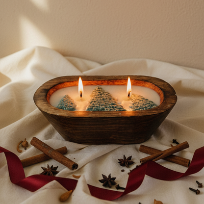 Wooden bowl with lit candles featuring Christmas tree designs on a white fabric background.