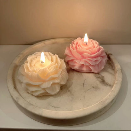 Two flower-shaped candles on a marble surface with a soft background