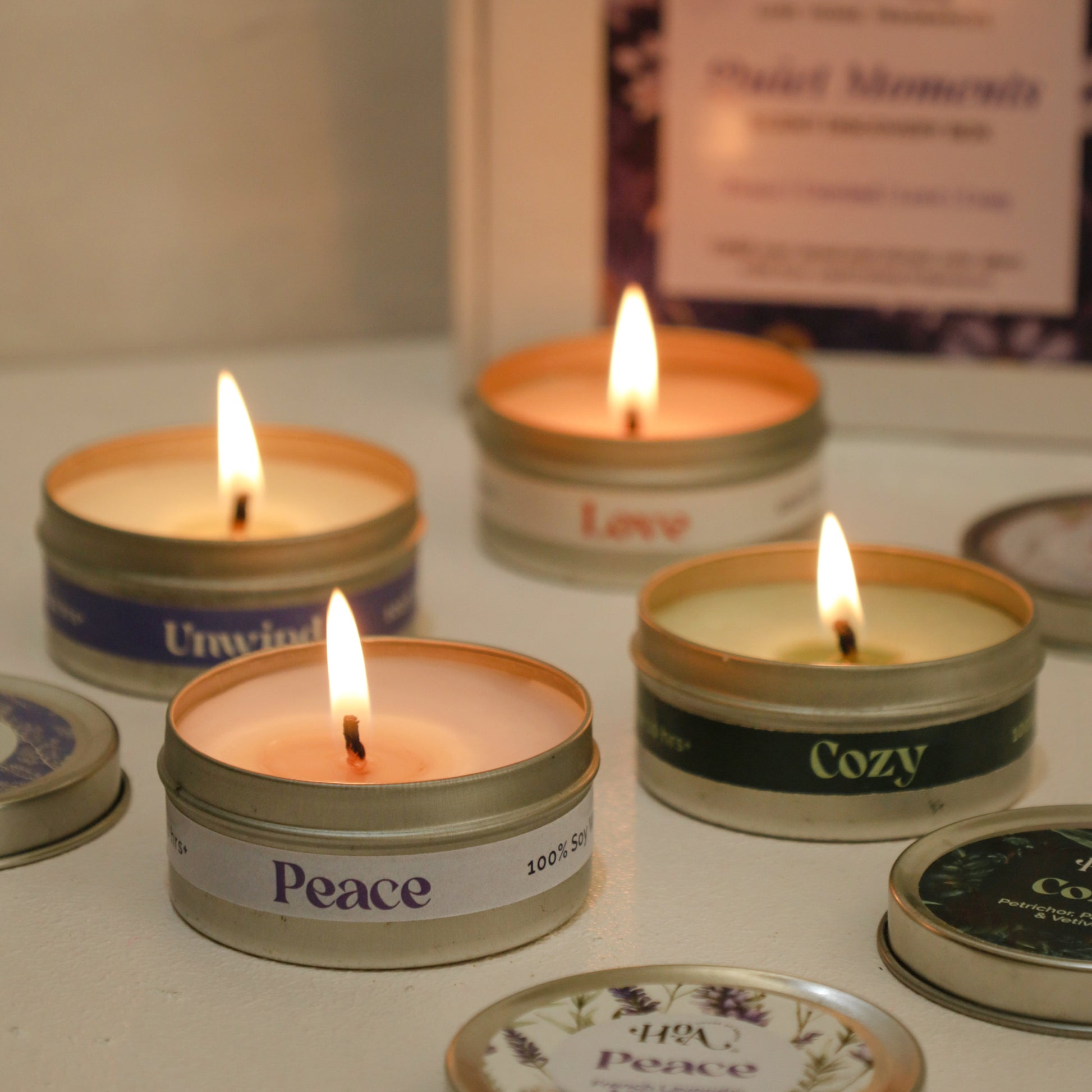 Small candles in tins with labels on a reflective surface