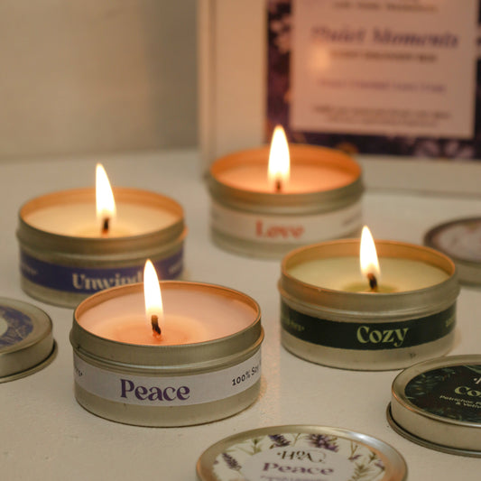 Small candles in tins with labels on a reflective surface