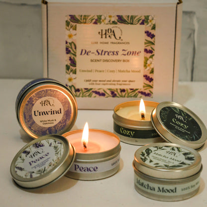 Set of small candles with lids featuring text, one lit, against a neutral background.