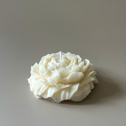 White flower-shaped candle on a beige background