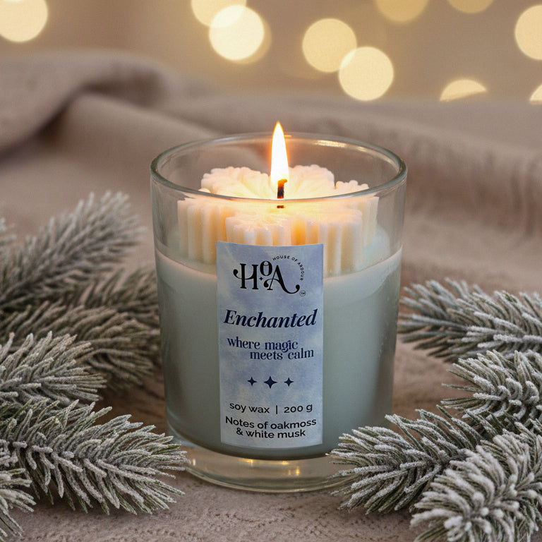 Candle in a glass jar with a label, surrounded by frosted branches and blurred lights in the background