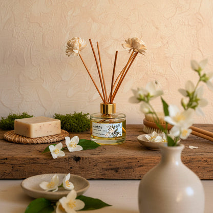 A still life arrangement with a diffuser, flowers, and a vase on a wooden surface.