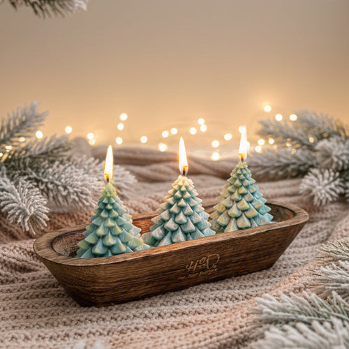Three pine tree-shaped candles in a wooden tray with a festive background